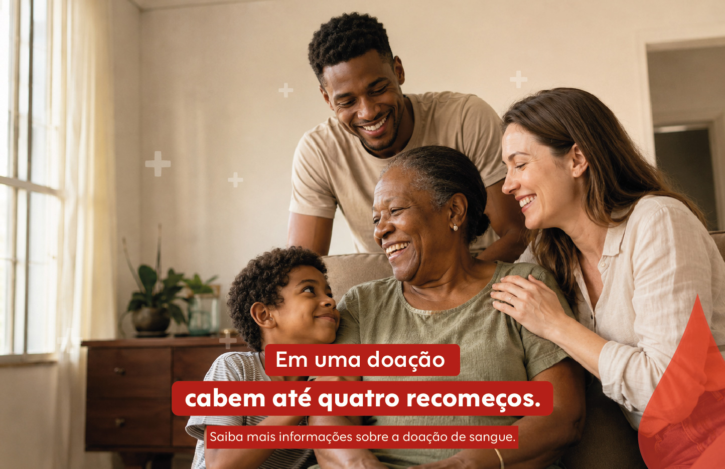 Aparece a imagem de uma família com quatro pessoas. Ao centro, uma mulher idosa está sentada e sorri. À sua esquerda, um menino olha para ela. Atrás dela, um homem jovem sorri. À direita, uma mulher jovem toca o ombro da idosa e sorri de perfil. No canto inferior direito, há o recorte geométrico de uma gota de sangue vermelha. As frases estão inseridas dentro de três faixas retangulares vermelhas com cantos arredondados, centralizadas na parte inferior da imagem: Em uma doação cabem até quatro recomeços. Saiba mais informações sobre a doação de sangue.